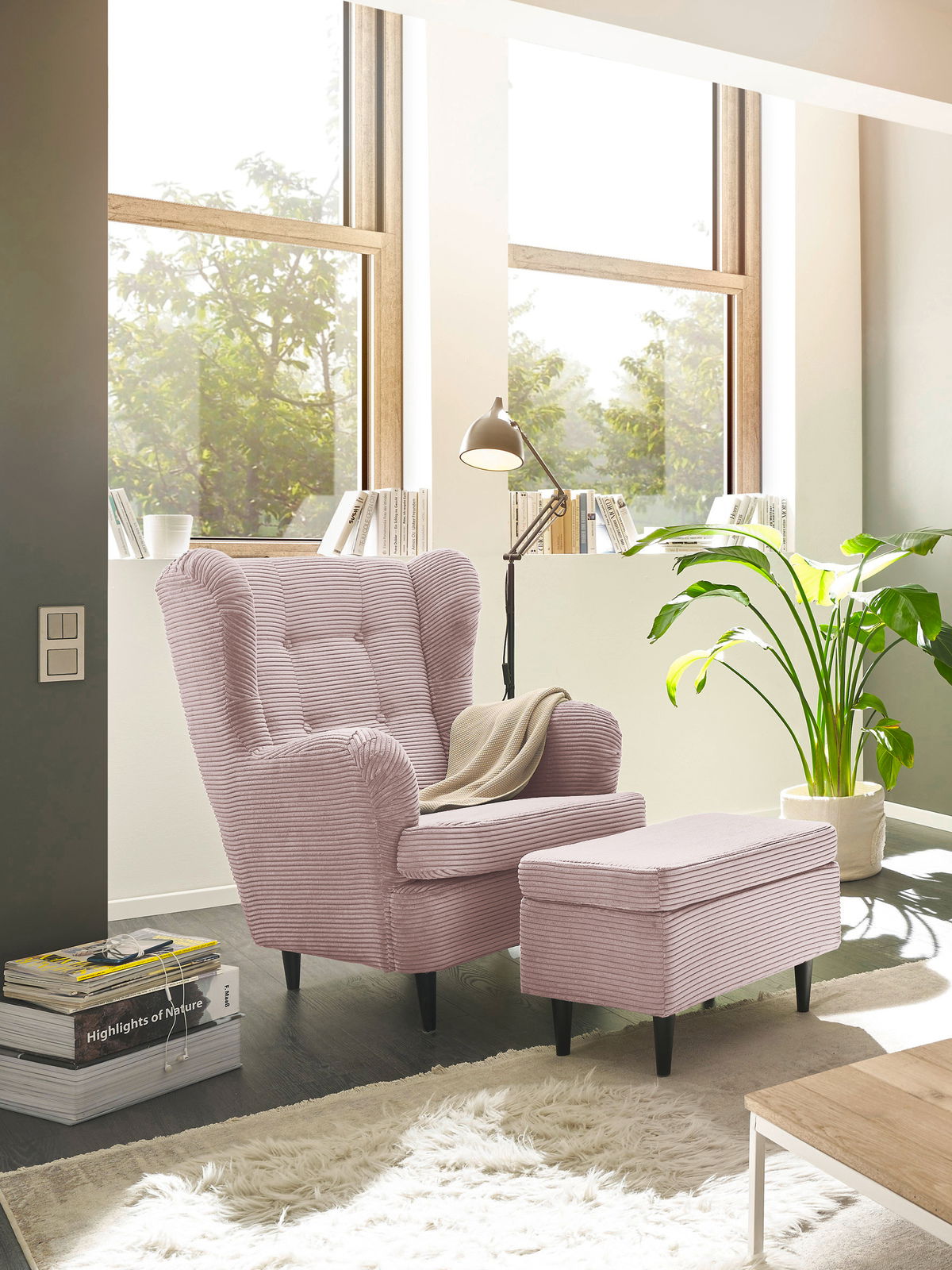 Gemütlicher rosa Sessel mit Hocker in einem hellen Wohnzimmer, seitliche Perspektive.