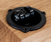 Close-up van een zwart rolmechanisme in een houten tafel, gezien van bovenaf.