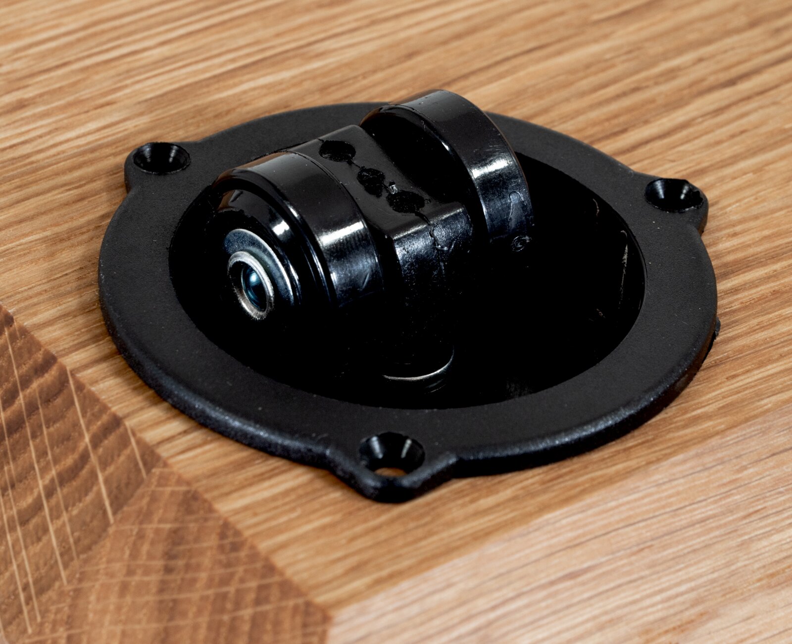 Close-up van een zwart rolmechanisme in een houten tafel, gezien van bovenaf.