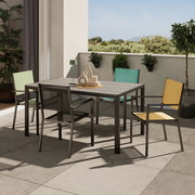 Moderner Gartentisch auf einer Terrasse mit vier bunten Stühlen, umgeben von Pflanzen, aus einer seitlichen Perspektive fotografiert.