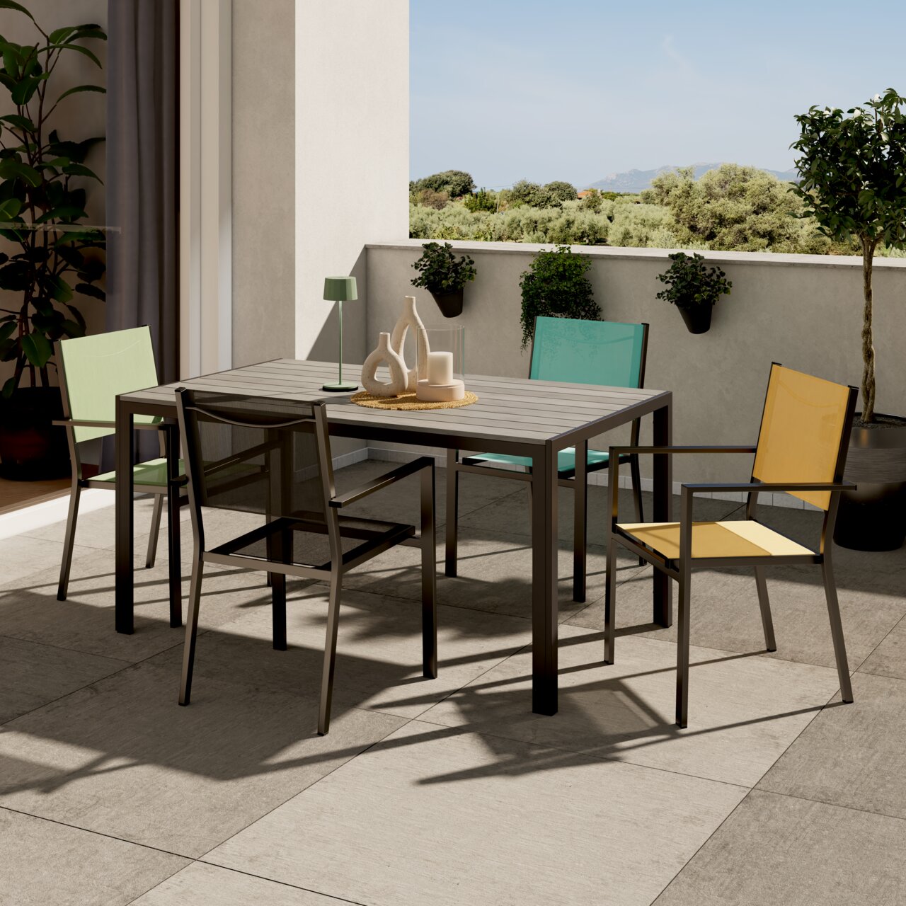 Ambia Garden Gartentisch VALENCIA Moderner Gartentisch auf einer Terrasse mit vier bunten Stühlen, umgeben von Pflanzen, aus einer seitlichen Perspektive fotografiert.
