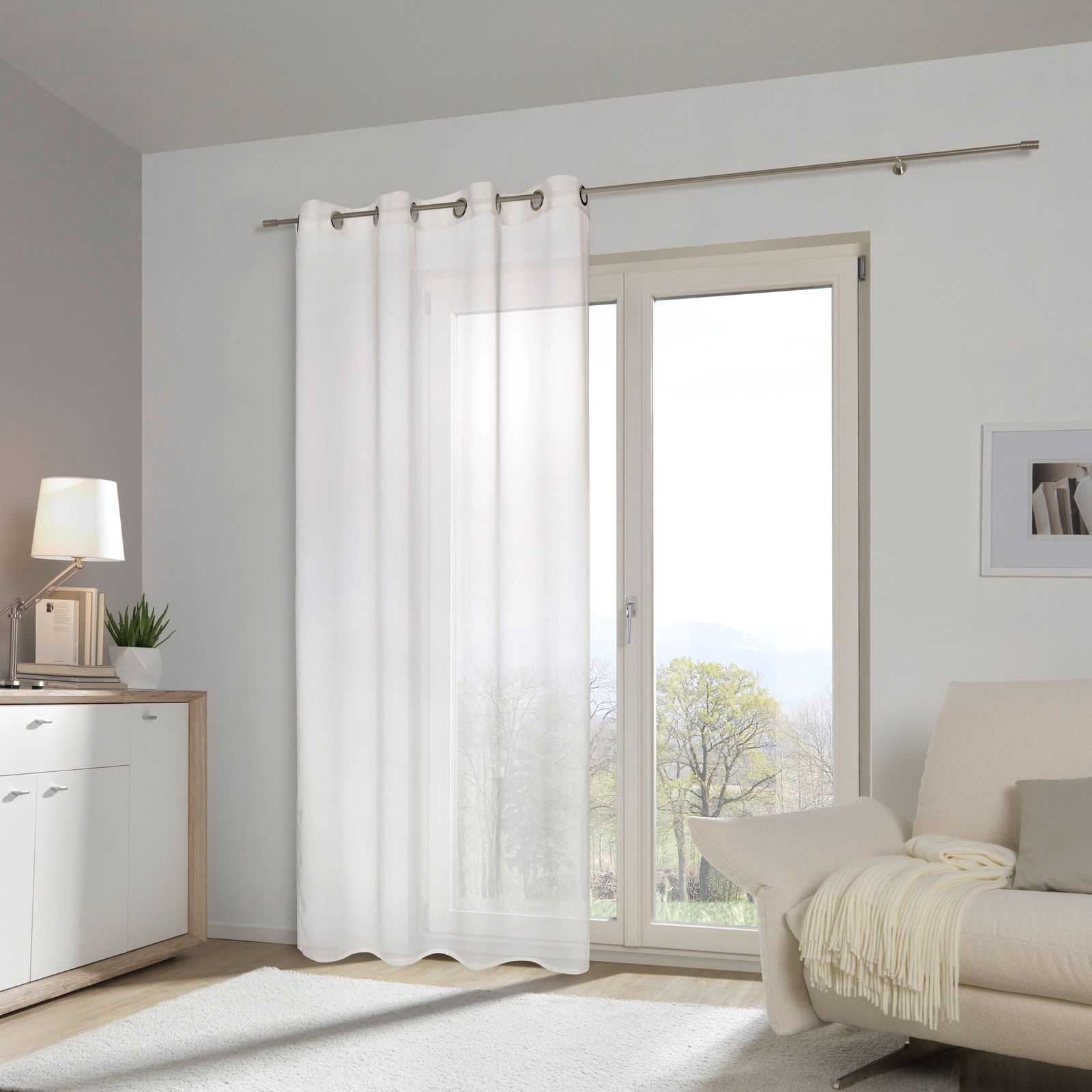 Weißer Ösenschal vor einem großen Fenster in einem modernen Wohnzimmer, seitliche Perspektive