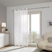 Witte sjaal met oogjes voor een groot raam in een moderne woonkamer, zijaanzicht