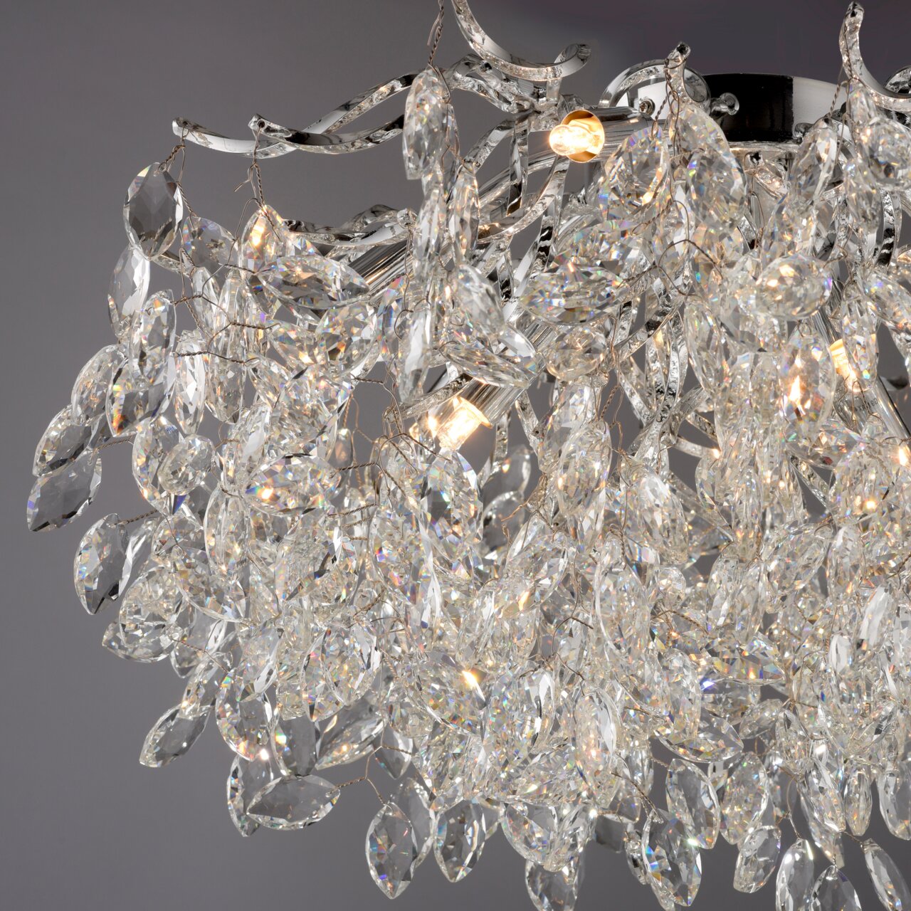 Nahaufnahme einer luxuriösen Deckenleuchte mit funkelnden Kristallen und eleganten Metallakzenten, seitliche Perspektive.