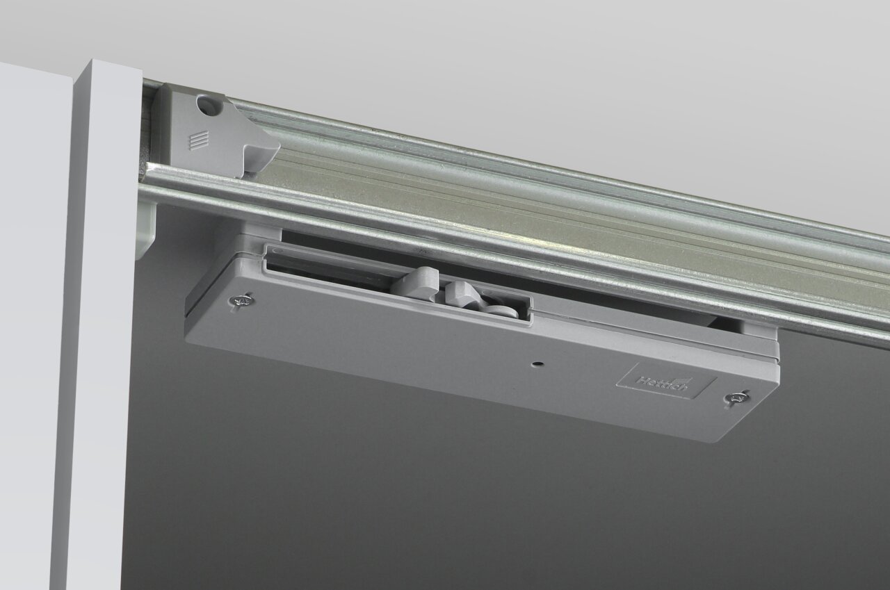 Nahaufnahme eines Schiebemechanismus für einen Dreh- und Schwebetürenschrank, von unten betrachtet.