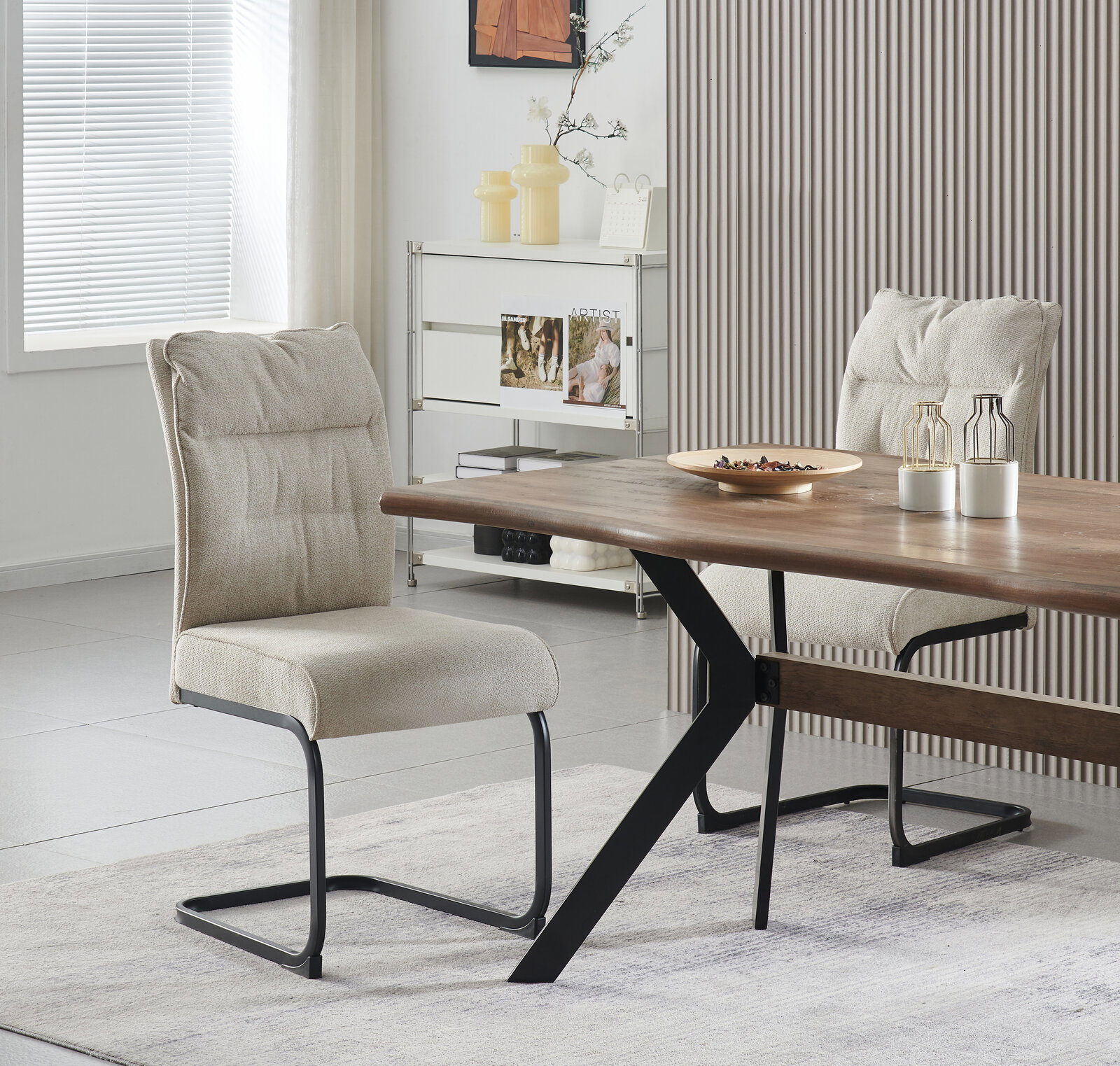 Schräg von vorn fotografierter Esszimmerstuhl mit hellbeigem Stoffbezug und schwarzem Metall-Schwinggestell an einem Holzesstisch in modernem Wohnraum