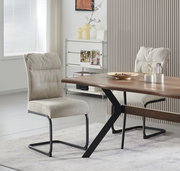 Schräg von vorn fotografierter Esszimmerstuhl mit hellbeigem Stoffbezug und schwarzem Metall-Schwinggestell an einem Holzesstisch in modernem Wohnraum