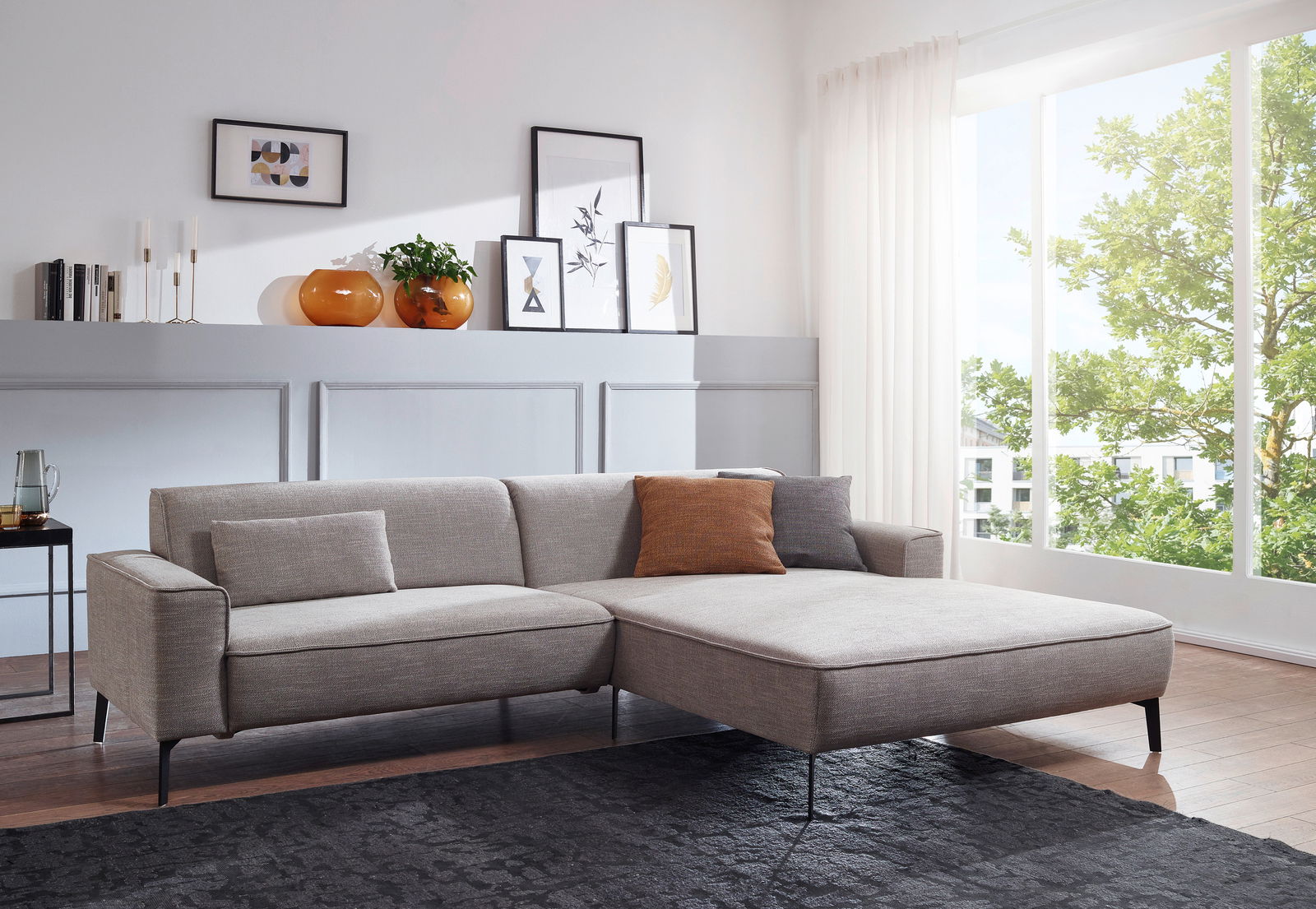 Graue Longchairkombination in einem modernen Wohnzimmer, seitliche Perspektive mit großen Fenstern im Hintergrund.