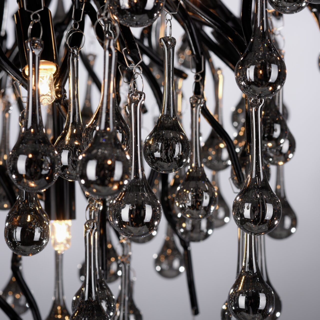 Close-up van de plafondlamp ICICLE met hangende, druppelvormige glazen elementen en stralende lampjes.
