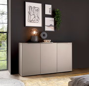 Modernes, hellgraues Sideboard mit drei Fronten vor dunkelgrauer Wand, dekoriert mit Tischlampe, Skulptur, Schale, gerahmten Bildern und hängender Pflanze; Perspektive: frontale Ansicht leicht von links auf Augenhöhe.