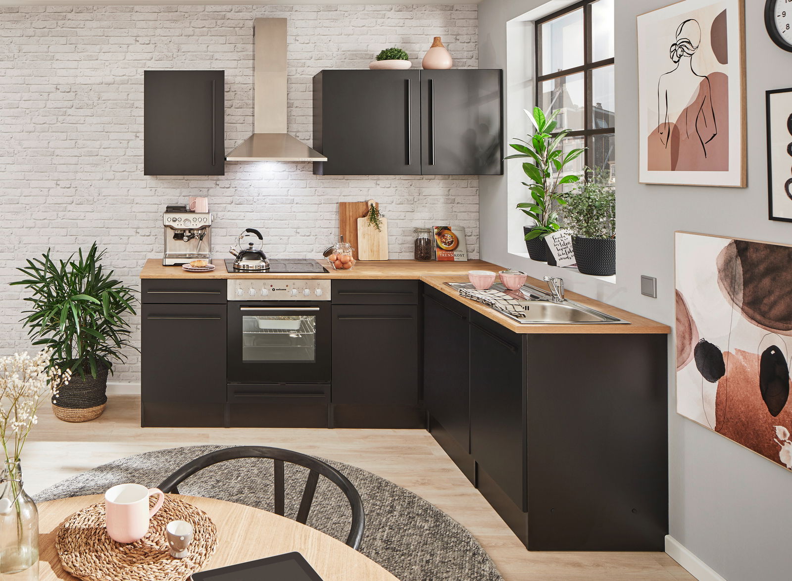 Moderne Küche mit schwarzem Eckunterschrank, Holzarbeitsplatte und Edelstahlspüle, aus der Perspektive von vorne rechts betrachtet.