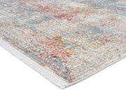 Designer Teppich mit buntem, abstraktem Muster in Rot-, Blau- und Gelbtönen, perspektivisch von der Seite fotografiert.