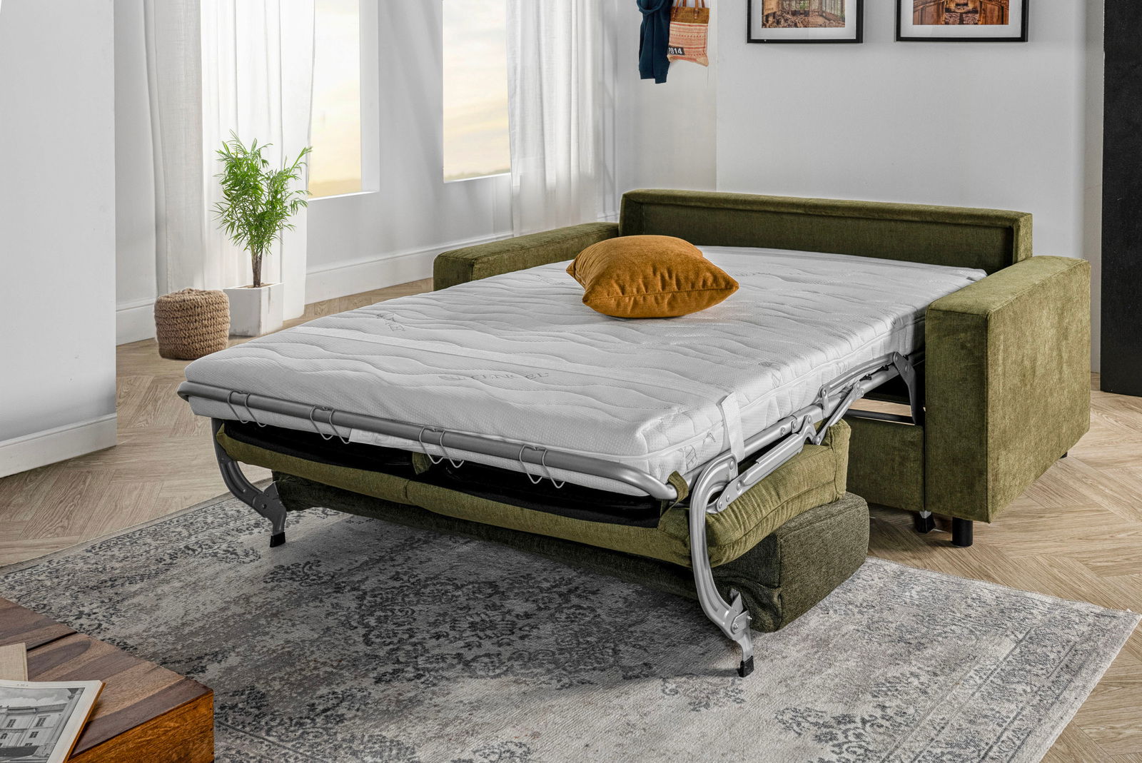 Grünes Funktionssofa in ausgeklappter Bettposition, seitliche Perspektive, mit weißer Matratze und einem senfgelben Kissen.