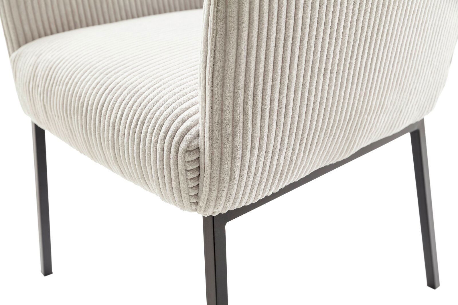 Nahaufnahme eines Sessels mit cremefarbenem, geripptem Stoffbezug und schwarzen Metallbeinen, seitliche Perspektive.