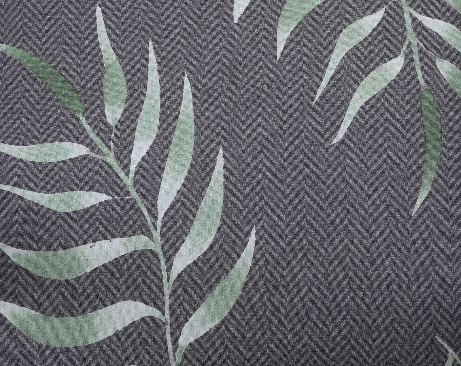 Nahaufnahme einer Mittellehnerauflage mit grünem Blattmuster auf grauem Hintergrund in Fischgrätmuster.