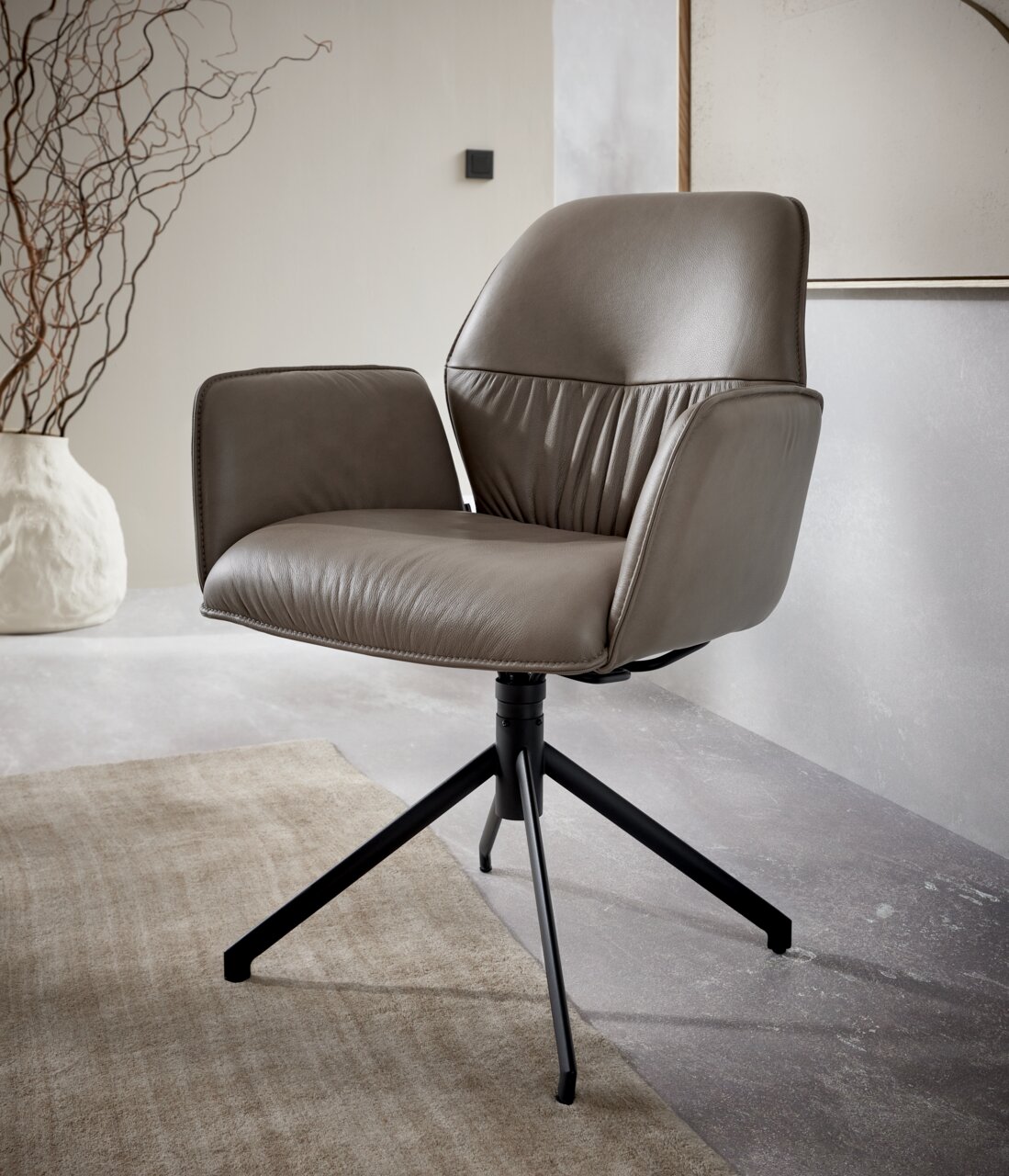 Moderne leren fauteuil in zijaanzicht, met een zwart metalen frame op tapijt.