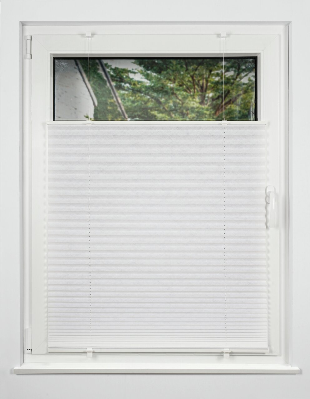 Plissee gefädelt 90x130cm in weiß, frontal an einem Fenster montiert, mit Blick auf einen Baum im Hintergrund.