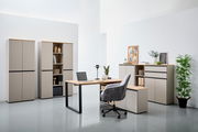 Moderne Büromöbel in einem hellen Raum, bestehend aus einem Winkelschreibtisch, mehreren Aktenschränken und einem Rollcontainer. Perspektive von vorne.