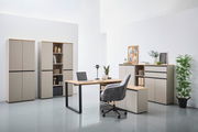 Moderne Büromöbel in einem hellen Raum, bestehend aus einem Winkelschreibtisch, mehreren Aktenschränken und einem Rollcontainer. Perspektive von vorne.