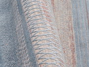 Nahaufnahme eines Designer-Teppichs mit geometrischem Muster in Blau- und Beigetönen, seitliche Perspektive