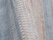 Nahaufnahme eines Designer-Teppichs mit geometrischem Muster in Blau- und Beigetönen, seitliche Perspektive