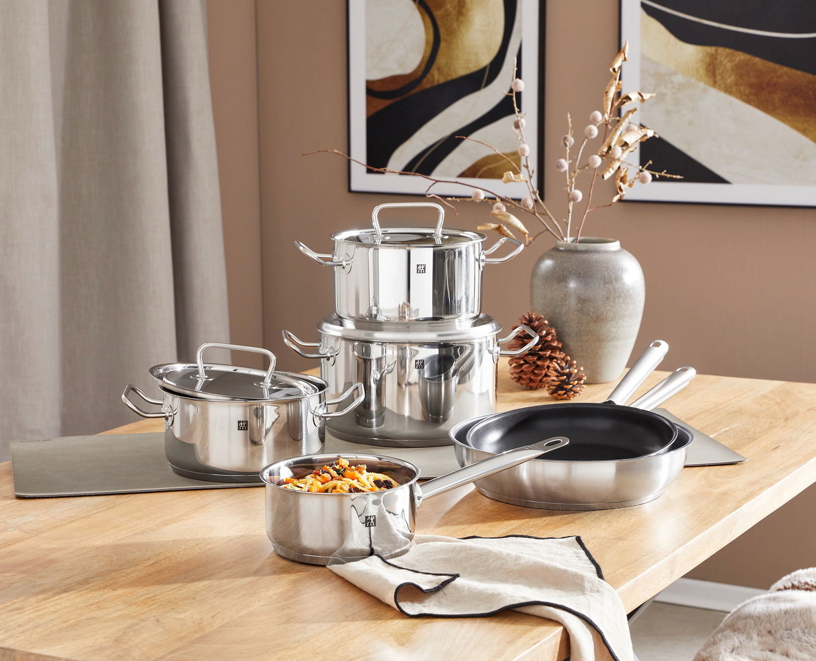 Topfset Twin Classic 6-tlg. aus Edelstahl, bestehend aus mehreren Töpfen und Pfannen, auf einem Holztisch in einer modernen Kücheneinrichtung, seitliche Perspektive.