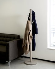 Moderner Garderobenständer aus Metall mit mehreren Haken, fotografiert aus seitlicher Perspektive neben einem Sofa und einem Fenster.