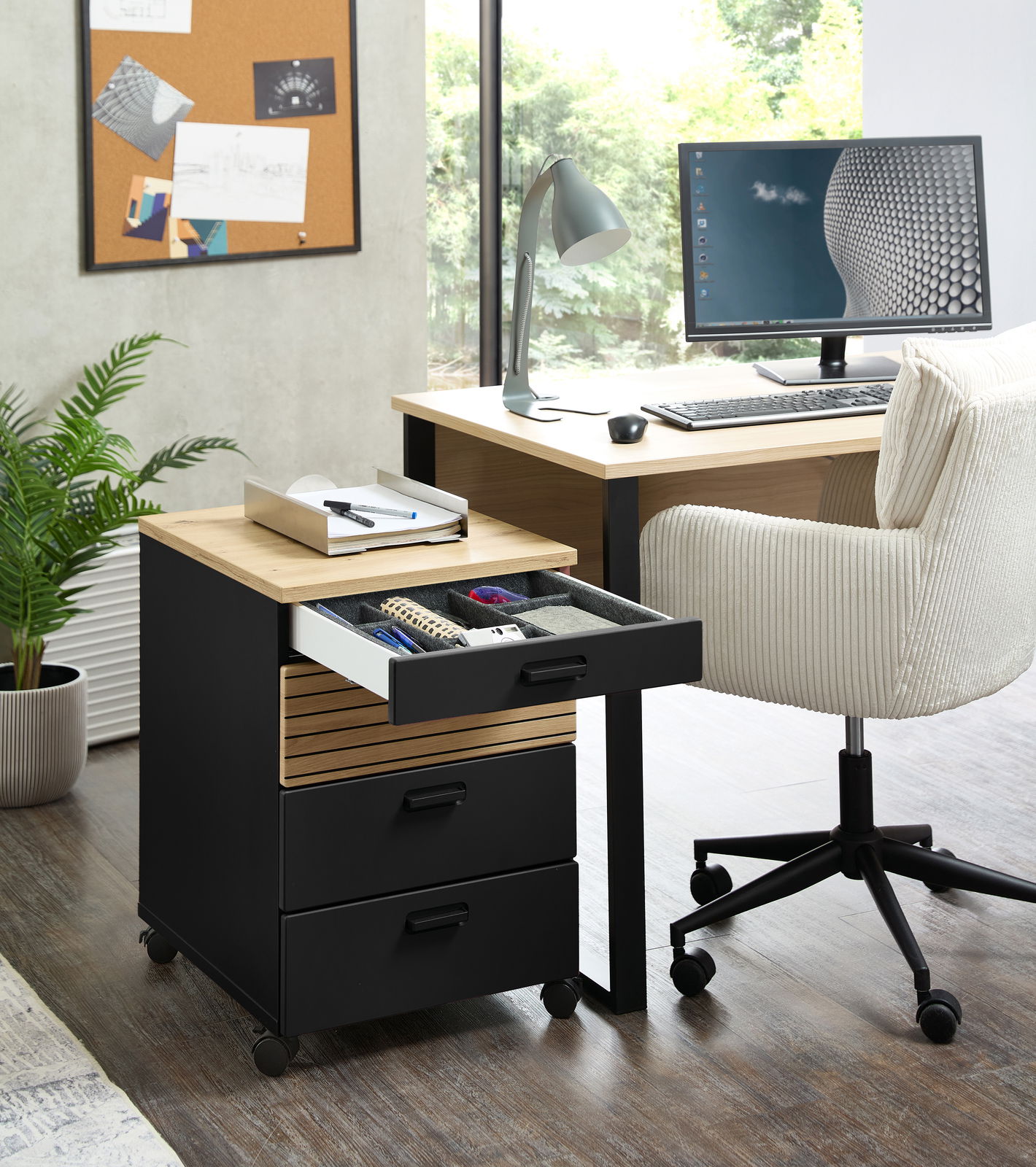 Rollcontainer mit drei Schubladen, teilweise geöffnet, in einem modernen Büro mit Schreibtisch und Stuhl, seitliche Perspektive