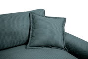 Nahaufnahme eines Big-Sofas mit geripptem Stoffbezug in Grün, inklusive passendem Kissen, seitliche Perspektive.