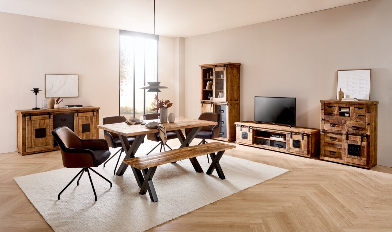 Esszimmer mit rustikalem Holztisch, Bank und Stühlen, umgeben von passenden Holzschränken und einem TV-Lowboard, seitliche Perspektive.