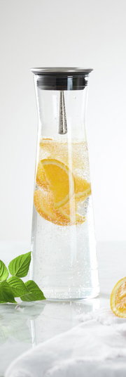 Karaffe mit 1,1 l Fassungsvermögen, gefüllt mit sprudelndem Wasser und Orangenscheiben, aus der Seitenperspektive fotografiert.