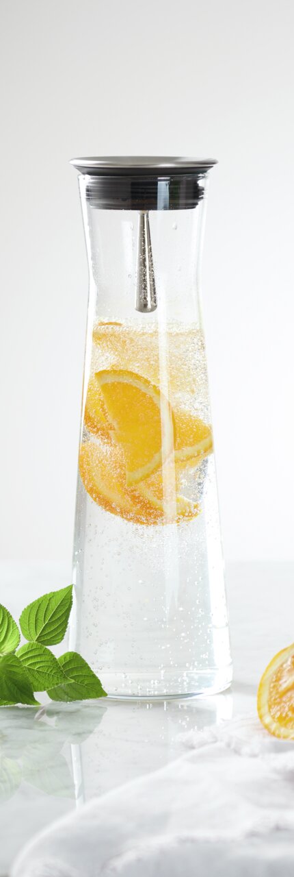 Karaf met een inhoud van 1,1 liter, gevuld met bruisend water en schijfjes sinaasappel, gefotografeerd vanuit een zijaanzicht.
