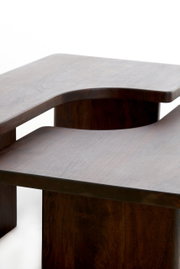 Moderner Couchtisch aus dunklem Holz mit geschwungenem Design, seitliche Perspektive
