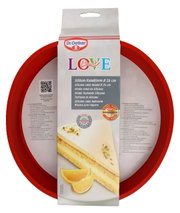 Rote Silikon-Rundform mit 26 cm Durchmesser, abgebildet in einer leicht schrägen Perspektive mit Verpackung von Dr. Oetker.