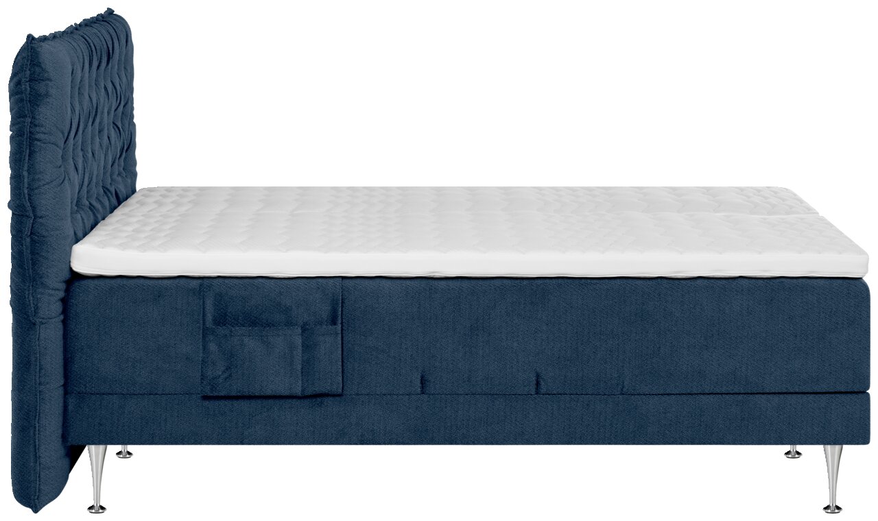 Blaues Boxspringbett mit gepolstertem, gestepptem Kopfteil und weißer Matratzenauflage, Seitenansicht von links vor weißem Hintergrund