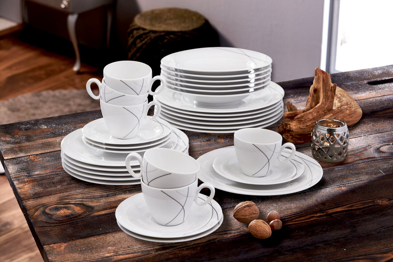Kombiservice Trio Highl. 30-teilig, bestehend aus elegantem weißen Geschirr mit feinen grauen Linien, auf einem rustikalen Holztisch arrangiert. Perspektive von schräg oben.