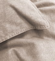 Nahaufnahme einer beigen Bettwäsche mit sichtbaren Nähten und Textur.