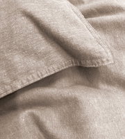 Nahaufnahme einer beigen Bettwäsche mit sichtbaren Nähten und Textur.