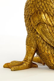 Detailansicht eines goldenen Tischleuchtenfußes in Form eines Vogels mit detaillierten Federn und Krallen.
