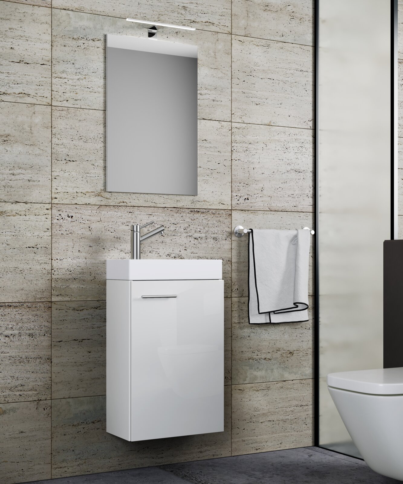 Modernes Badezimmer-Set mit wandhängendem weißem Waschtischunterschrank, Aufsatzwaschbecken, Chromarmatur und Spiegel mit LED-Leuchte vor beiger Steinfliesenwand, Frontansicht leicht seitlich von links