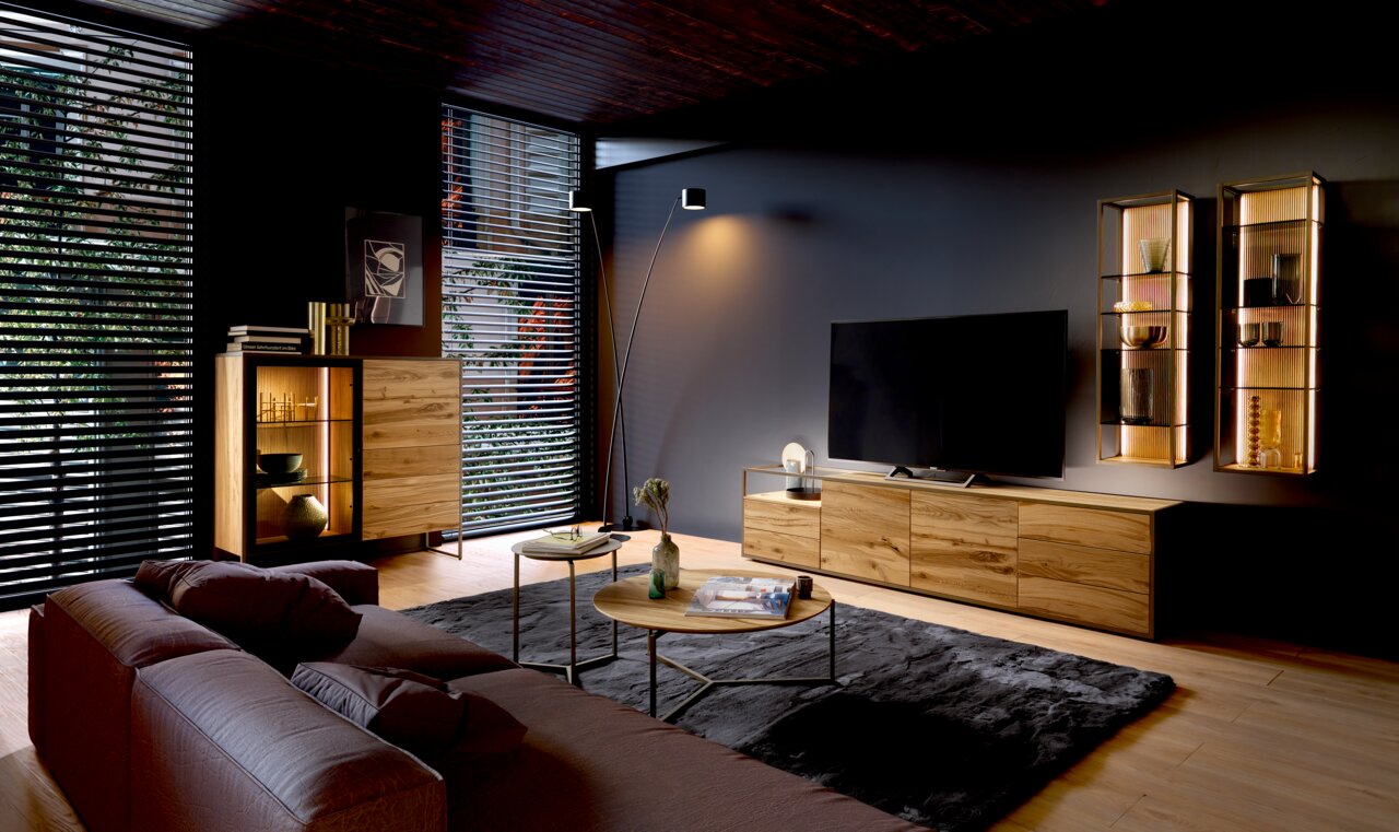 Venjakob Hangende plank TAGENA Moderne woonkamer met een houten hoogkast, een grote tv op een dressoir en twee verlichte hangende planken aan de muur. Aanzicht vanaf de zijkant.