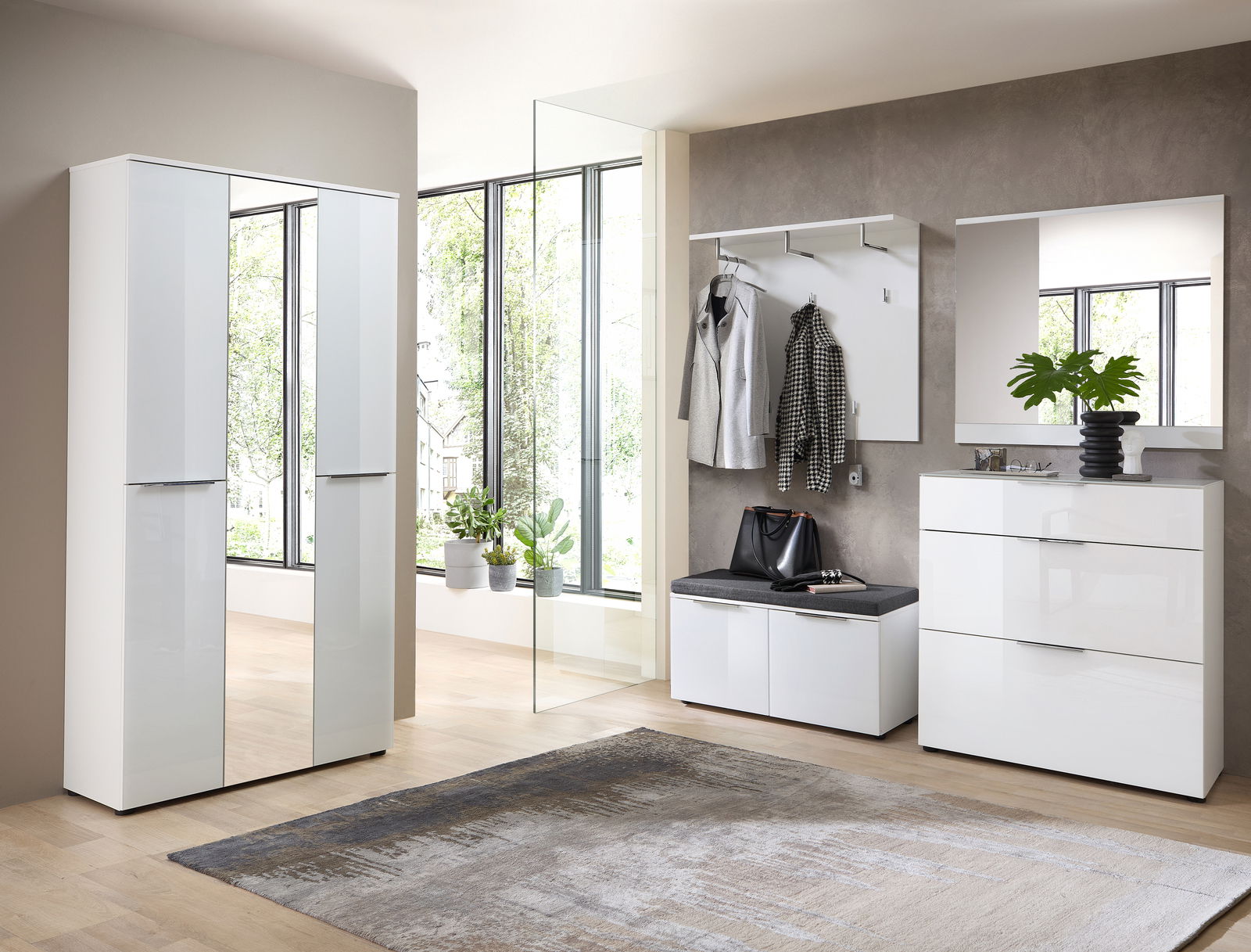 Moderne Garderobeneinrichtung mit weißem Hochglanz-Schrank, Spiegel, Garderobenpaneel und Bank in einem hellen Raum mit großen Fenstern, seitliche Perspektive.