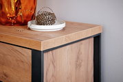 Nahaufnahme eines Sideboards aus Holz mit schwarzem Metallrahmen, darauf eine orangefarbene Vase und eine Schale mit Schnur, Perspektive von oben.