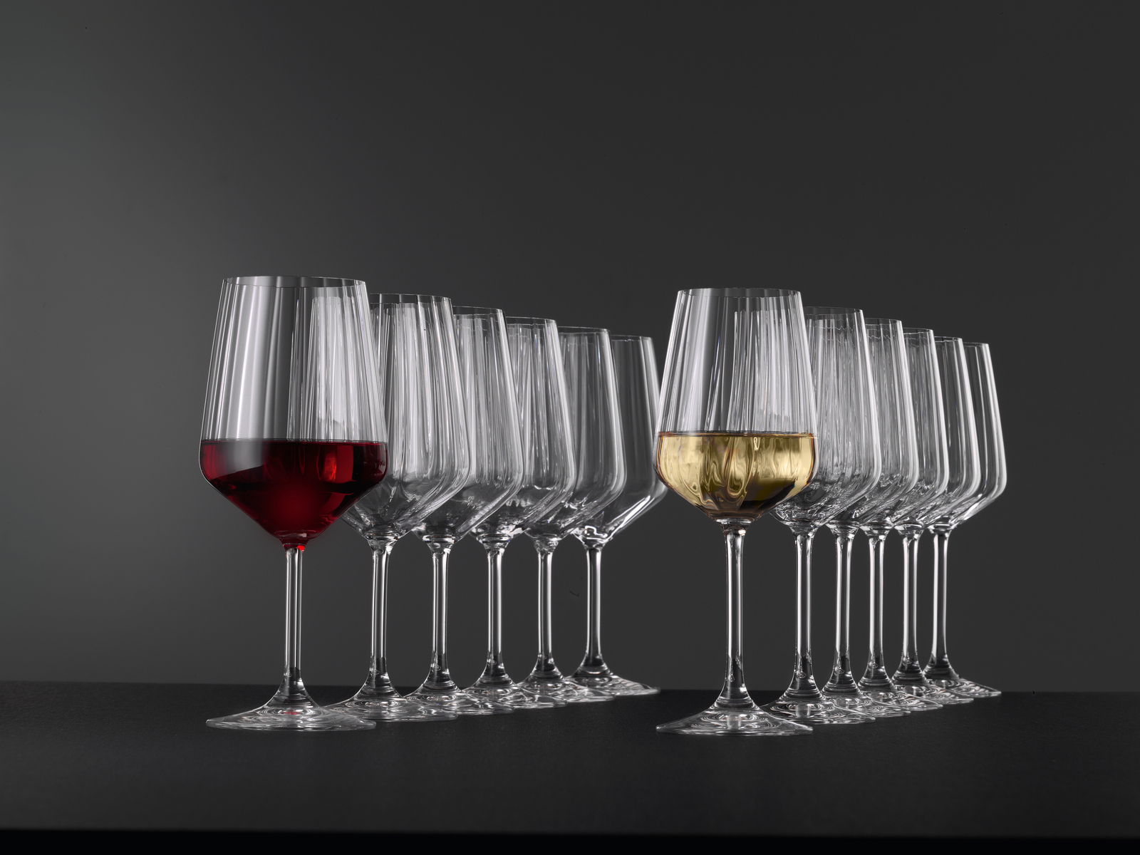 Stielglas Set mit 12 Gläsern, gefüllt mit Rot- und Weißwein, seitliche Perspektive