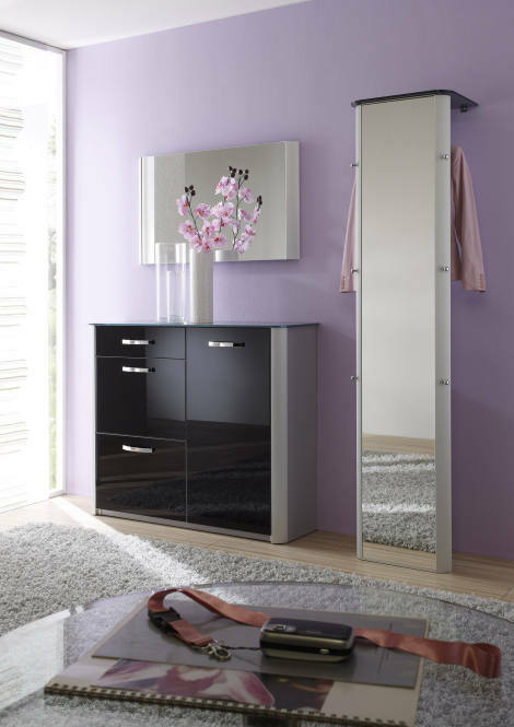 Moderner, schmaler Standspiegel in einem eleganten Raum mit lila Wand und schwarzem Schrank, seitliche Perspektive.