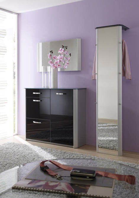 Moderner, schmaler Standspiegel in einem eleganten Raum mit lila Wand und schwarzem Schrank, seitliche Perspektive.