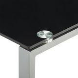 Nahaufnahme eines modernen Schreibtischs mit schwarzer Glasplatte und silbernem Metallrahmen, Perspektive von oben auf die Ecke.