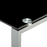 Close-up van een modern bureau met een zwart glazen blad en een zilverkleurig metalen frame, gezien van bovenaf op de hoek.