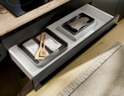 Ausziehbare Küchenschublade mit zwei Organizer-Schalen, Holz-Kochutensilien und gefalteten Tüchern in moderner Küche, Perspektive schräg von oben