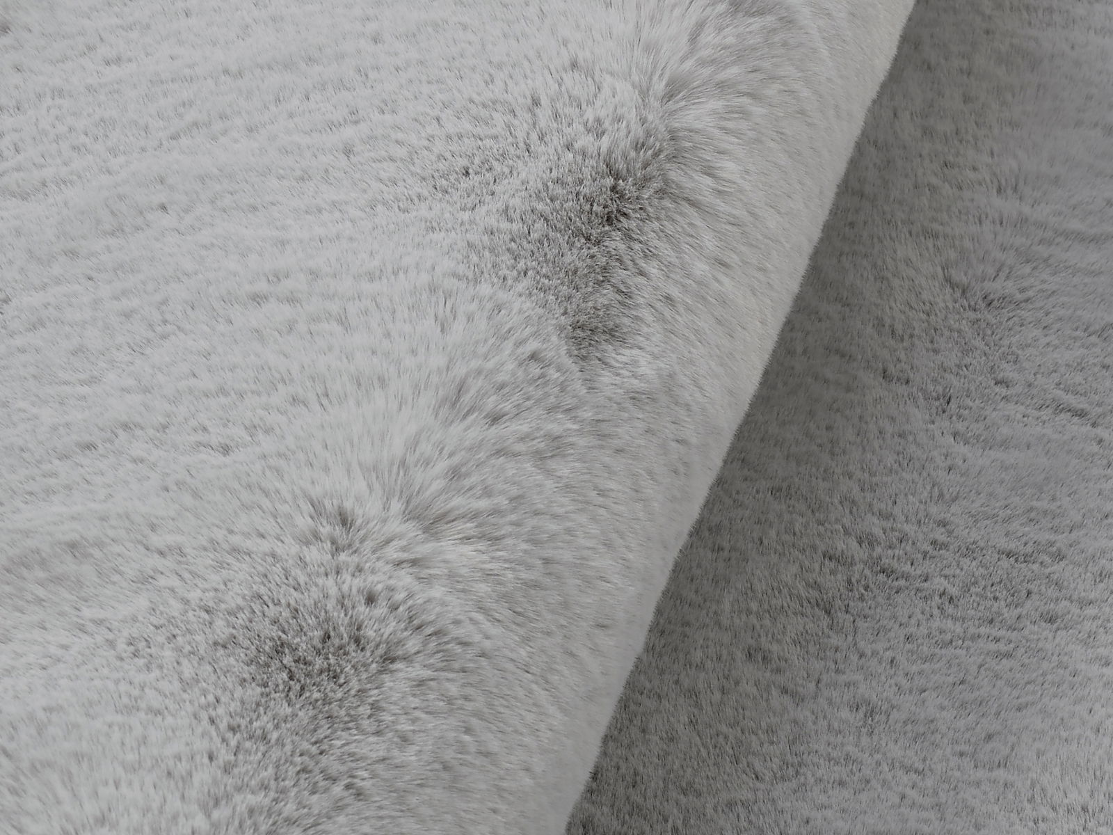 Nahaufnahme eines grauen Fellteppichs mit weicher Textur, seitliche Perspektive
